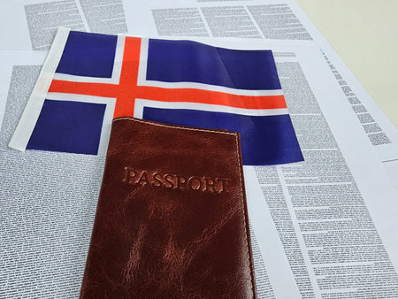 Icelandic passport placed on a newspaper next to the Icelandic flag, representing travel and culture