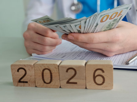 Healthcare professional counting cash while planning for the year 2026 with financial documents on...