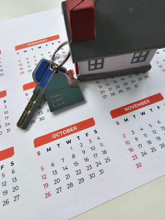 Keychain and miniature house on calendar highlighting October dates for home events and planningの写真素材