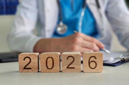 Wooden blocks show the year 2026 in a doctor office. A healthcare is seen in the backgroundの写真素材