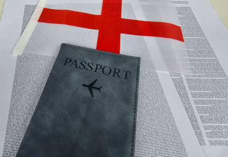 Passport rests on printed document with English flag in background, symbolizing travel and cultureの写真素材