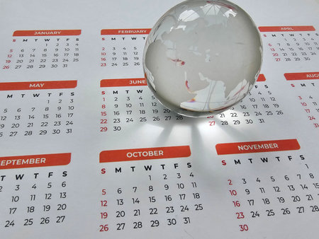 Calendar with crystal globe highlighting global connections and time managementの写真素材