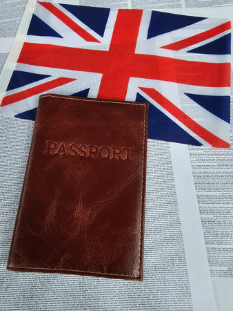 British passport resting on a newspaper with a UK flag background