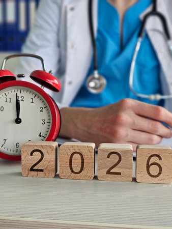 Doctor setting goals for patient care in 2026 with clock and wooden blocksの写真素材