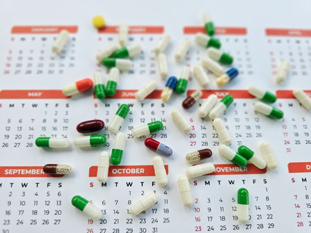 Scattered capsules on a calendar marking important dates throughout the yearの写真素材