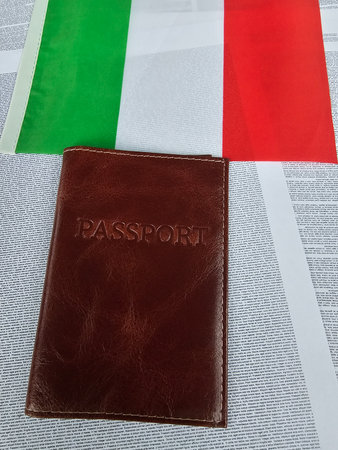 Passport resting on a newspaper background with an Italian flag forming part of the sceneの写真素材