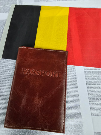 Passport rests on a collage of newspaper and the Belgian flag showing national identityの写真素材