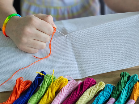 Hand stitching with colorful threads during a creative crafting session at homeの写真素材