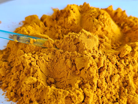 Yellow turmeric powder in a heap ready for culinary and medicinal use in various dishes