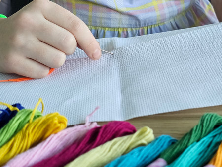 Hand sewing project in a cozy setting with colorful threads and an eager young hand