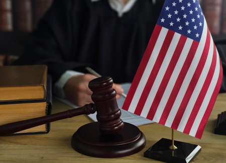 Judge presiding over court session with American flag and legal books in the backgroundの写真素材