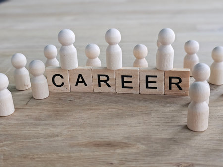 Wooden figurines surround the word career displayed on blocks in a creative arrangement on a wooden tableの写真素材