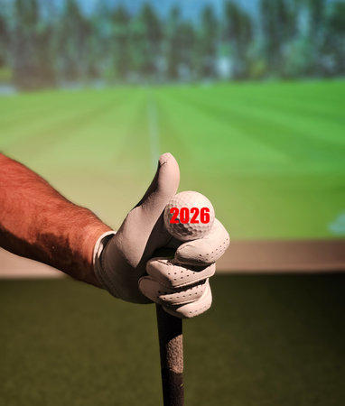 Golfer prepares to swing while using a simulator in indoor golf facility during evening hours in 2026の写真素材
