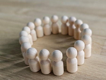 Group of wooden figures arranged in a circular formation on a wooden surface during daylightの写真素材