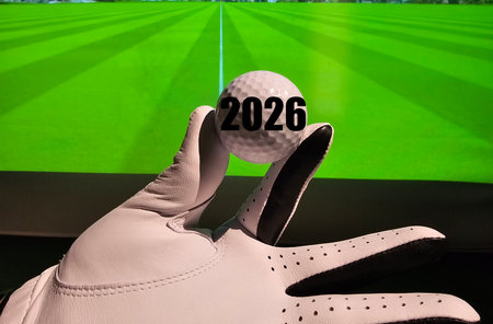 Golf enthusiast displaying a ball marked with the year 2026, preparing for an indoor practice sessionの写真素材
