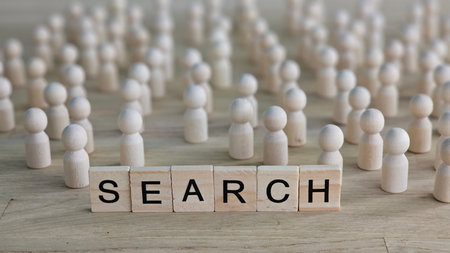 Wooden figures gather around the word search on a wooden surface, emphasizing exploration and curiosity in a creative setupの写真素材