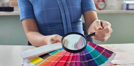 Color selection process with swatches and magnifying glass during design work in a bright workspaceの写真素材