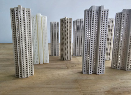 Model buildings arranged on a wooden surface in various heights and colors with a simple backgroundの写真素材