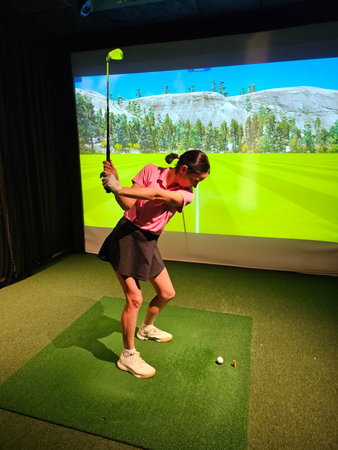 Golf swing practice inside a simulator with a virtual course displayed on the screenの写真素材