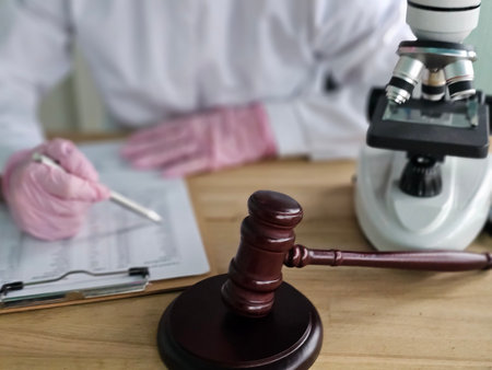 Doctor and lawyer working together to analyze medical evidence using a microscope and legal documentsの写真素材