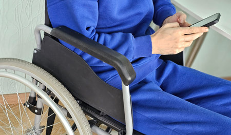 Person in a wheelchair using a smartphone in a cozy indoor setting