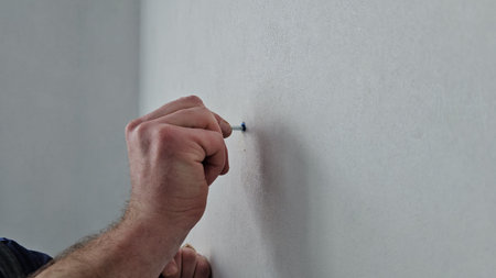 Person marking a wall for a picture frame at a home in the afternoon light during home improvement...
