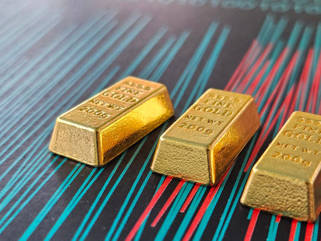 Gold bars are placed on a colorful background showing designs and numbers related to finance and investmentの写真素材