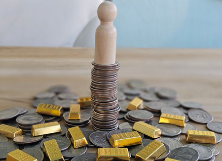 Stack of coins and gold bars with a wooden figure in the center on a wooden table