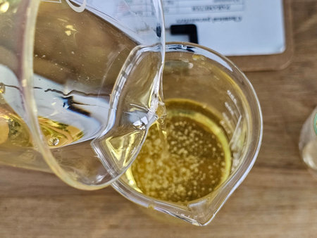 A technician pours a yellow oily liquid from one glass to another. He conducts a scientific experiment with the colored liquid and petroleum products in the laboratory.の写真素材