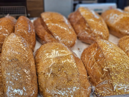 Bakery scene showing freshly baked bread loaves wrapped in plastic on display in a food market...