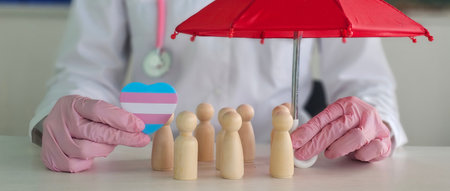 A healthcare worker holds a red umbrella over wooden figures, showing a heart symbol for inclusivity...