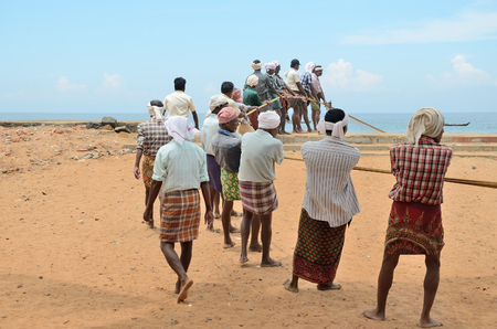 Traditional fishermen are pulling the seine fishing net from the sea in the beach of Kovalam.のeditorial素材