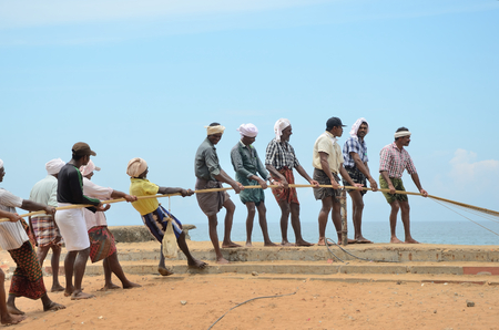 Traditional fishermen are pulling the seine fishing net from the sea in the beach of Kovalam.のeditorial素材
