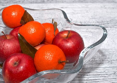 vase with apples and mandarin oranges on a wooden backgroundの写真素材