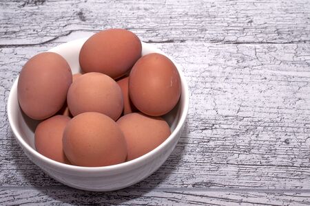 eggs cooked for Easter, in a white bowl on a wooden tableの写真素材