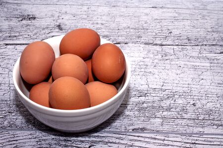 eggs cooked for Easter, in a white bowl on a wooden tableの写真素材