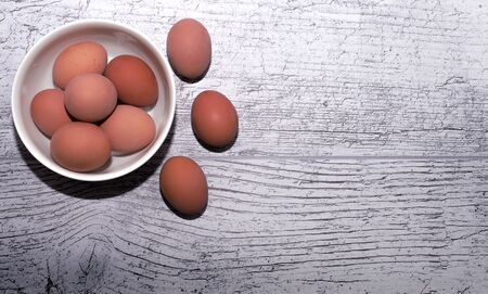 eggs cooked for Easter, in a white bowl on a wooden tableの写真素材