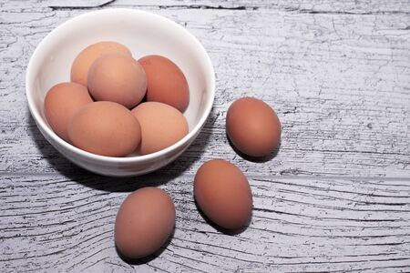 eggs cooked for Easter, in a white bowl on a wooden tableの写真素材
