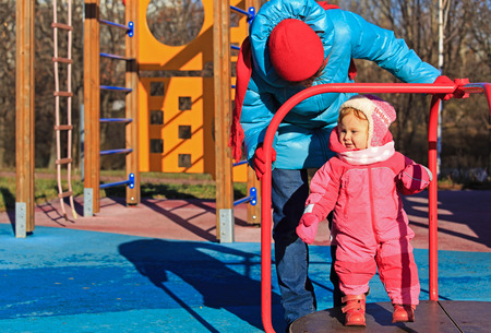 little girl playing on outdoor playground in autumnの写真素材
