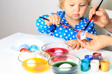 mother and little daughter painting eggs, easter holidayの写真素材