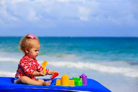 cute little girl playing with toys on tropical beachの写真素材