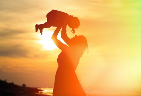 mother and little daughter play at sunset beachの写真素材