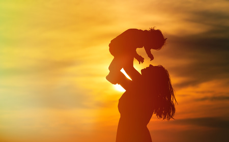 happy mother and little daughter play at sunsetの写真素材
