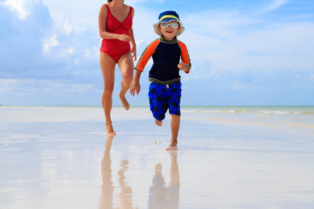 mother and son running in water on tropical beachの写真素材