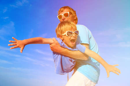 Father and little son playing on blue summer skyの写真素材