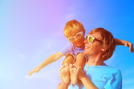 Father and little son playing on blue summer skyの写真素材