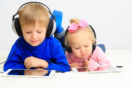 little boy and toddler girl with headset using touch pad, early education and learningの写真素材