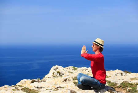 young man doing yoga in summer mountains