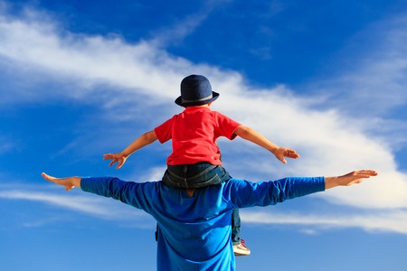 happy father and little son on shoulders play on skyの写真素材