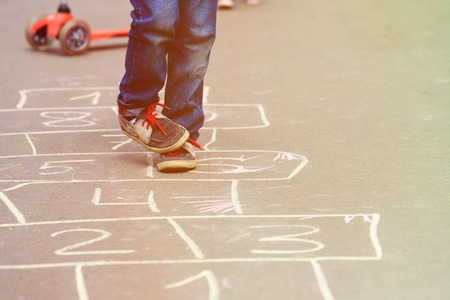 little boy playing hopscotch on playground outdoorsの写真素材